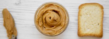 Fıstık ezmesi, ekmek ve beyaz ahşap zemin, üstten görünüm üzerinde bıçak. Yukarıdan.