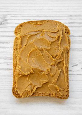 Fıstık ezmesi beyaz ahşap yüzey, en iyi görünüm üzerinde tek tost. Düz, tepegöz, yukarıdan yatıyordu.