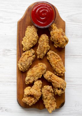 Ketçap Beyaz ahşap zemin üzerinde bir rustik ahşap tahta üzerinde tavuk kanatları. Yakın çekim.