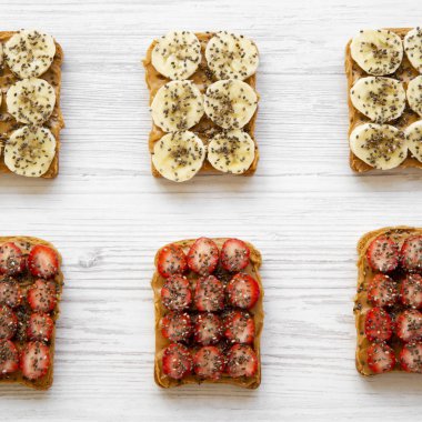 Fıstık ezmesi, meyve ve bir beyaz tahta yüzey, en iyi görünümde chia tohum ile tost. Yukarıdan. Sağlıklı Kahvaltı, diyet kavramı. Yakın çekim.