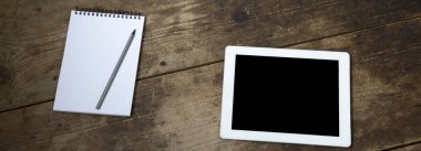 Tablet: Not defteri ve kalem koyu ahşap arka plan, düşük açılı görünümü ile.