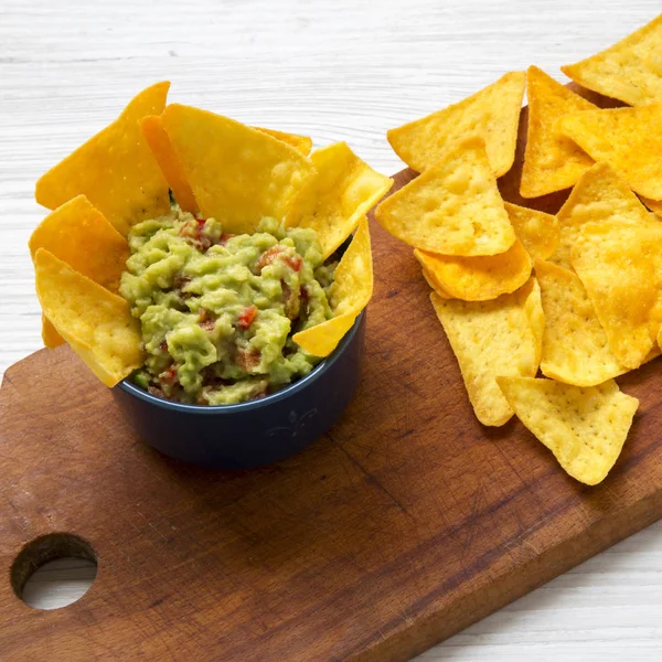 Geleneksel Meksika guacamole rustik ahşap tahta, yan görünüm üzerinde Mısır cips ile. 