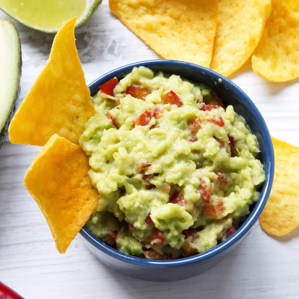Guacamole malzemeler ve Mısır nachos üzerinde beyaz ahşap yüzey, düşük açılı görünüş. Yakın çekim.