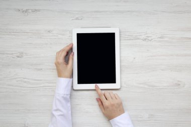 Tablet bir beyaz ahşap masa, üstten görünüm kullanma eller. Yukarıdan, tepegöz, düz yatıyordu.