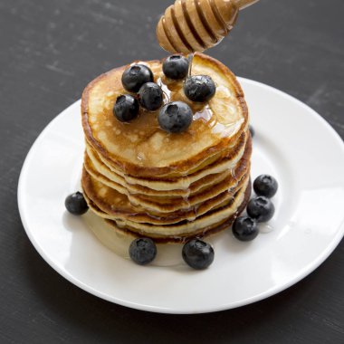 Yaban mersini ve ballı bir beyaz krep plaka koyu siyah arka plan üzerinde yan görünüm yuvarlak. Yakın çekim. 