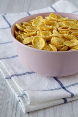 Beyaz ahşap arka plan, yan görünüm kahvaltıda için pembe bir kase mısır gevreği. 