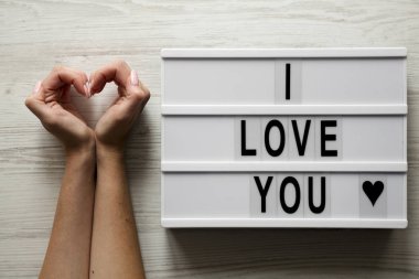 Modern 'I Love You', kalp şeklinde eller üzerinde beyaz ahşap yüzey, en iyi görünümü metin ile kurulu. Yukarıda, ek yükü. Sevgililer günü.