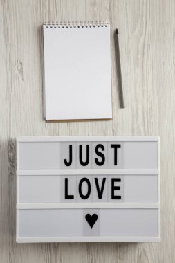 Metin 'Just love', Not defteri ve kalem Beyaz ahşap zemin, üstten görünüm üzerinde modern yönetim kurulu. Düz lay, ek yükü. Sevgililer günü 14 Şubat.