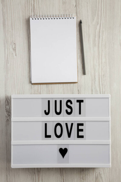 Modern board with text 'Just love', notepad and pencil on a white wooden background, top view. Flat lay, overhead. Valentine's Day 14 February.