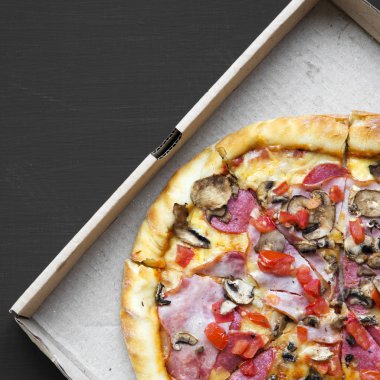 Bir karton kutu siyah arka plan, havai görünümü üzerine taze pişmiş pizza. Yukarıdan yatıyordu, en iyi görünüm, düz.