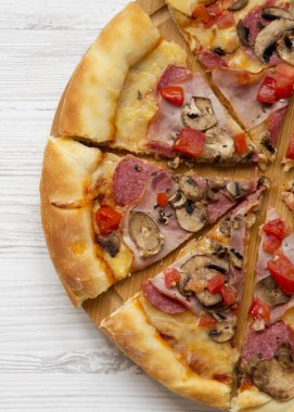 Beyaz ahşap arka plan, üstten görünüm üzerinde yuvarlak bambu tahta üzerinde taze pişmiş pizza. Yukarıdaki üzerinden düz lay. 