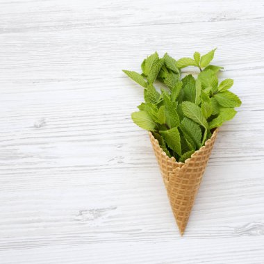 Gözleme tatlı koni nane ile beyaz ahşap zemin üzerinde üstten görünüm bırakır. Yukarıdan Lay, düz. Yaz arka plan. Kopya alanı.