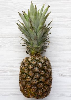Beyaz ahşap bir masa üzerinde olgunlaşmış ananas. Yukarıdan. Üstten görünüm, ek yükü.