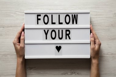 Eller 'Sen kalbini Beyaz ahşap arka plan üzerinde takip' metin ile modern yönetim kurulu tutun. Portre.