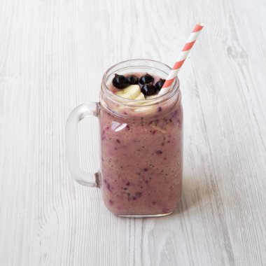 Siyah frenk üzümü ve muz Beyaz ahşap arka planda, yan görünümü ile güler yüzlü.