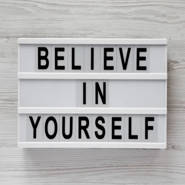 \'Believe in yourself\' word on modern board on a white wooden background, top view. From above, flat lay, overhead.