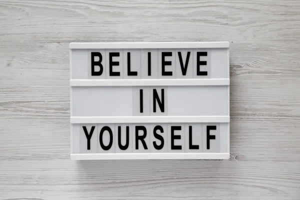 \'Believe in yourself\' word on modern board on a white wooden surface, top view. From above, flat lay, overhead.