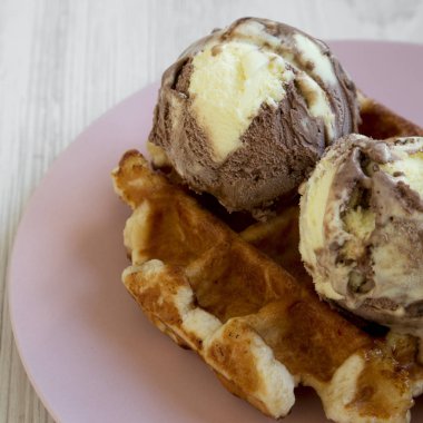 Beyaz ahşap arka plan, yan görünüm üzerinde pembe plaka üzerinde dondurma ile geleneksel Belçika waffle. Portre.