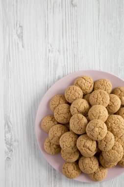 Bademli kurabiyeleri Beyaz ahşap arka plan, üstten görünüm üzerinde pembe plaka üzerinde. Düz, tepegöz, yukarıdan yatıyordu. Kopya alanı.