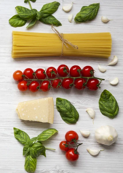 Beyaz ahşap bir masa havai görünümü üzerinde makarna yemek pişirmek için malzemeler. Yukarıdaki üzerinden düz lay.