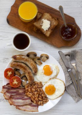 Tam İngiliz kahvaltısı kızarmış yumurta, sosis, pastırma, fasulye ve tost Beyaz ahşap zemin üzerinde. Üstten görünüm, ek yükü.