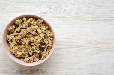 Beyaz ahşap masa, üstten görünüm üzerinde pembe kase meyve granola. Yukarıdan, ek yük düz yatıyordu. Kopya alanı.