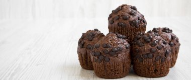 Beyaz ahşap masa, yan görünüm üzerinde çikolata cupcakes. Metin için yer.