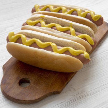 Rustik tahtada beyaz ahşap masa, yan görünüm üzerinde sarı hardallı Hotdog. Yakın çekim.