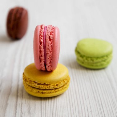 Tatlı ve beyaz ahşap zemin, yan görünüm üzerinde renkli macarons. Seçici odak. Yakın çekim.