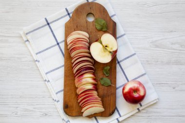 Beyaz ahşap masa, üstten görünüm üzerinde rustik ahşap tahta üzerinde taze kırmızı elma dilimleri. Yukarıdan, ek yük düz lay.
