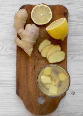 Beyaz ahşap bir masa üstten görünüm üzerinde rustik ahşap tahta üzerinde limon ile ev yapımı zencefil çayı fincan. Üstten, yukarıdaki.