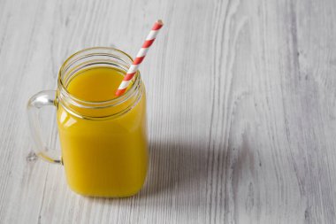 Cam kavanoz içinde beyaz ahşap arka plan, düşük açılı görünümü taze portakal suyu. Kopya alanı.