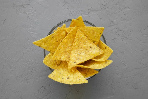 Full bowl of tortilla chips on concrete background, top view. Mexican food. From above, overhead.