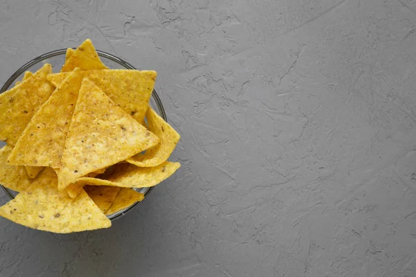 Full bowl of tortilla chips on gray background, top view. Mexican food. From above, overhead. Copy space.