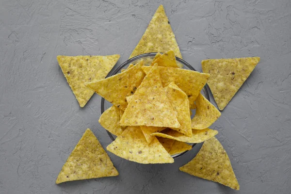 Tortilla chips in glass bowl over gray background, top view. Mexican food. From above, overhead.