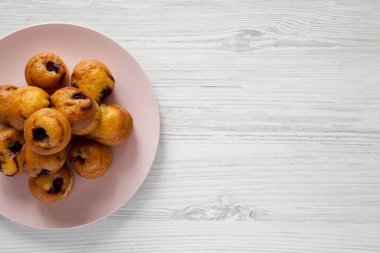 Üstten görünüm, Beyaz ahşap zemin üzerinde pembe plaka üzerinde kiraz ile ev yapımı mini kekler. Düz, tepegöz, yukarıdan yatıyordu. Kopya alanı.