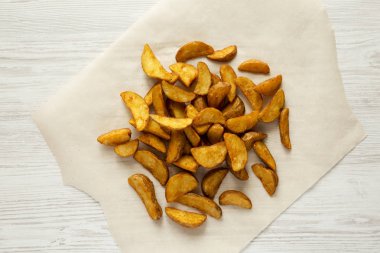 Üstten görünüm, kızarmış patates dilimleri bir beyaz tahta yüzey üzerinde. Yukarıda, ek yükü. Yakın çekim.