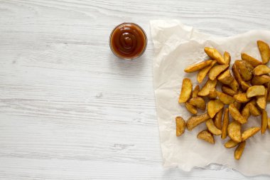Beyaz ahşap zemin üzerinde Barbekü soslu kızarmış patates dilimleri. Yukarıdan, tepegöz, görünümü top. Kopya alanı.