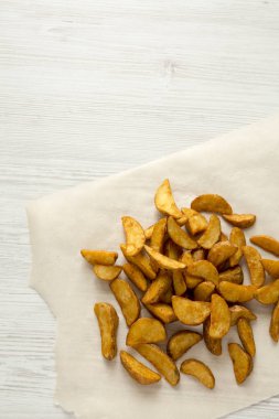 Üstten görünüm, kızarmış patates dilimleri Beyaz ahşap zemin üzerinde. Yukarıda, ek yükü. Kopya alanı.
