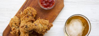 Kızarmış tavuk drumsticks ketçap ve soğuk bira üzerine beyaz ahşap arka plan, havai görünümü.