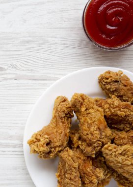 Beyaz ahşap masa, üstten görünüm üzerinde soslu ile yuvarlak beyaz tabakta tavuk kanatları. Tepegöz, yukarıdan lay, düz. 