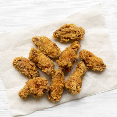 Kağıt tepsisine Beyaz ahşap yüzeye, havai görünümü üzerinde kızarmış tavuk kanatları. Yukarıdan, ana sayfa görünümü.