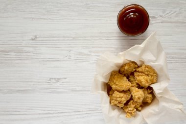 Kağıt kutusunda, Beyaz ahşap arka plan, üstten görünüm üzerinde Barbekü soslu kızarmış tavuk alıntılar. Düz, tepegöz, yukarıdan yatıyordu. Kopya alanı.