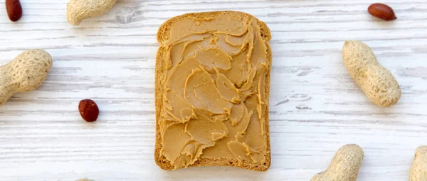 Toast with peanut butter on a white wooden table, top view. Close-up. From above, flat lay, overhead.