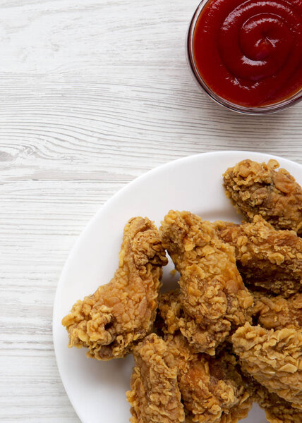 Куриные крылышки на круглой белой тарелке с соусом над белым деревянным столом, вид сверху. Накладные, плоские, сверху
. 