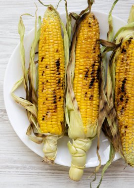 Üstten Görünüm üzerinde beyaz bir plaka üzerinde ızgara mısır. Düz-lay, genel gider. Yakın çekim.