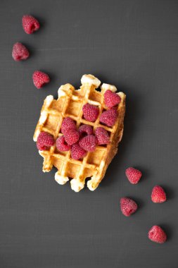 Siyah arka plan üzerinde ahududu ile geleneksel Belçika waffle. Düz, Tepegöz, yukarıdan yatıyordu. 