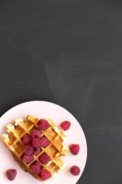 Siyah arka plan, üstten görünüm üzerinde pembe plaka üzerinde ahududu ile geleneksel Belçika waffle. Düz, Tepegöz, yukarıdan yatıyordu. Kopya alanı.