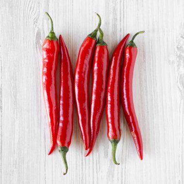 Beyaz ahşap bir masa, ek yükü üzerinde sıcak kırmızı pul biber. Yukarıdan, üstten görünüm, düz yatıyordu. Yakın çekim.