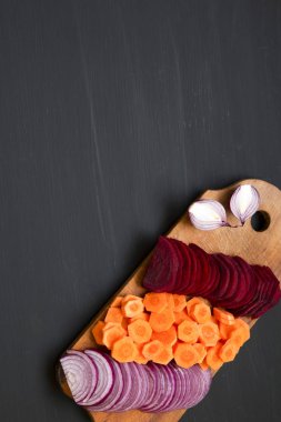 Koyu arka plan üzerinde rustik ahşap tahta üzerinde kıyılmış taze sebze. Üstten Görünüm. Yukarıdan. Kopya alanı.